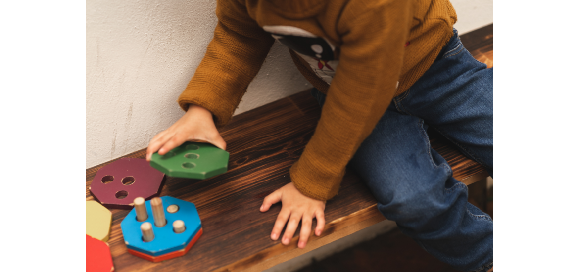 Niño pequeño jugando con piezas de encaje de madera de colores, actividad común en terapias de estimulación temprana para niños con autismo.