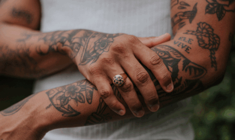 La imagen muestra un primer plano de los brazos de una persona con múltiples tatuajes.